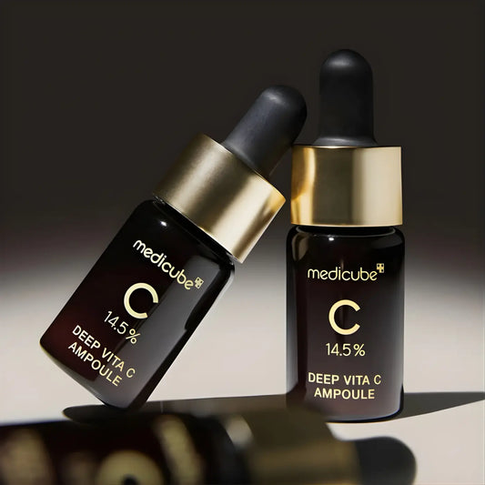 Two dark glass bottles with gold caps and black droppers labeled medicube deep vita c ampoule 14.5 percent