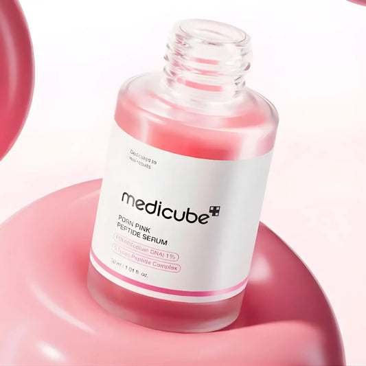 A clear glass bottle of pdrn pink peptide serum 30ml with white label pink accents and translucent pink liquid