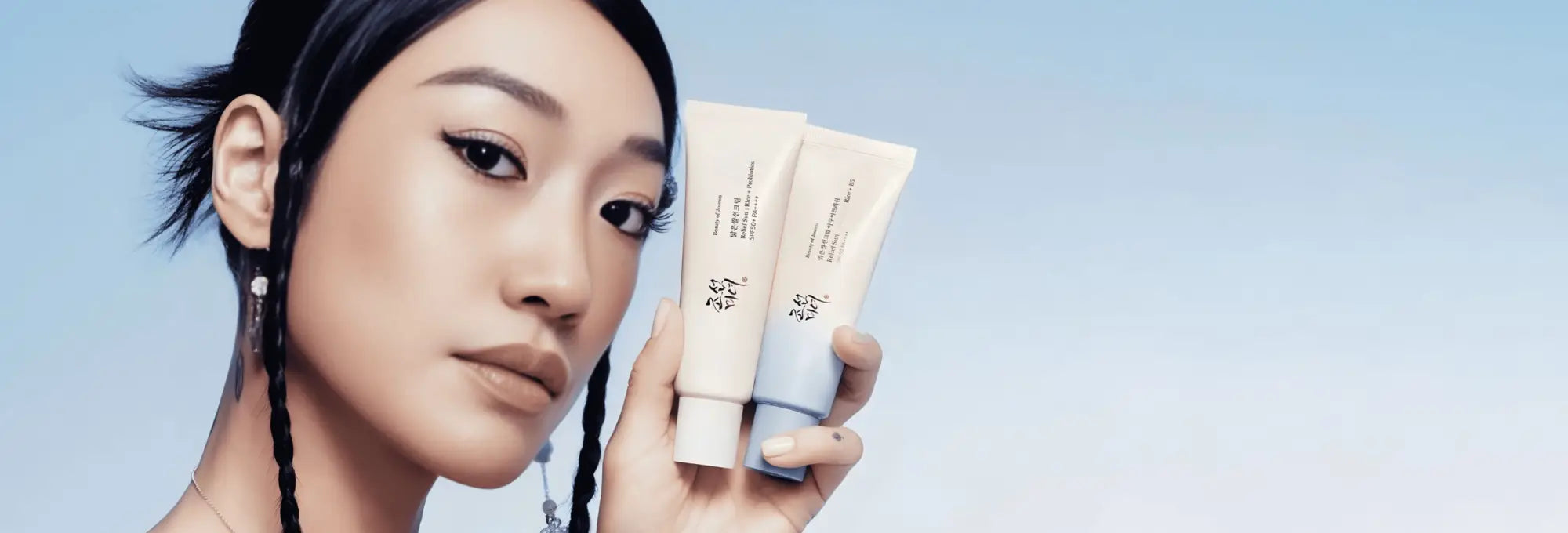 Two sleek white and light blue korean sunscreen tubes held in hand showcasing authentic korean skincare south africa options