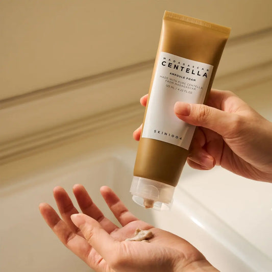 A gold-colored tube of skin1004 madagascar centella ampoule foam with a white label and clear flip-top cap