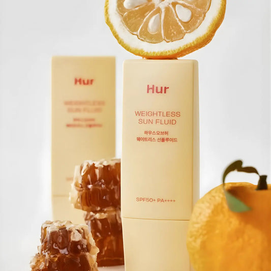 Creamy beige rectangular bottle of weightless sun fluid sunscreen spf 50 pa plus plus plus topped with citrus slice